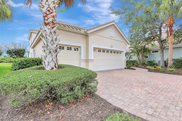 12710 Stone Ridge Pl, Lakewood Ranch, FL 34202 - view of front of home with stucco siding, an attached garage, decorative driveway, and a tiled roof