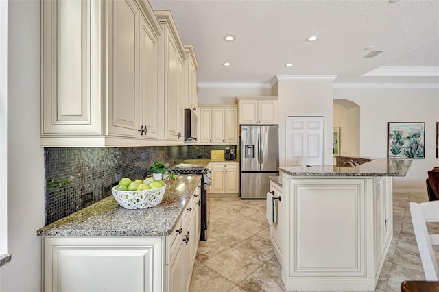 12710 Stone Ridge Pl, Lakewood Ranch, FL 34202 - kitchen featuring stainless steel appliances, cream cabinets, arched walkways, backsplash, and stone countertops