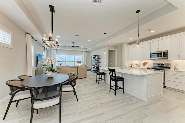 909 Crosswind Ave, Sarasota, FL 34240 - kitchen with appliances with stainless steel finishes, light wood-type flooring, light countertops, a kitchen island with sink, and recessed lighting