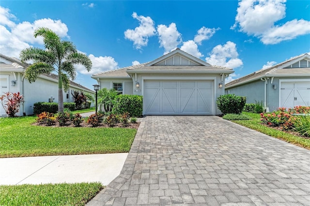 909 Crosswind Ave, Sarasota, FL 34240 - single story home with decorative driveway, a front lawn, an attached garage, and stucco siding