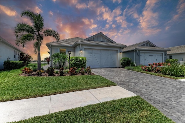 909 Crosswind Ave, Sarasota, FL 34240 - ranch-style home with decorative driveway, an attached garage, a yard, and stucco siding