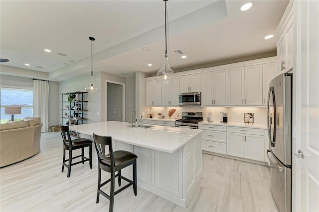 909 Crosswind Ave, Sarasota, FL 34240 - kitchen featuring appliances with stainless steel finishes, a sink, open floor plan, decorative backsplash, and white cabinets