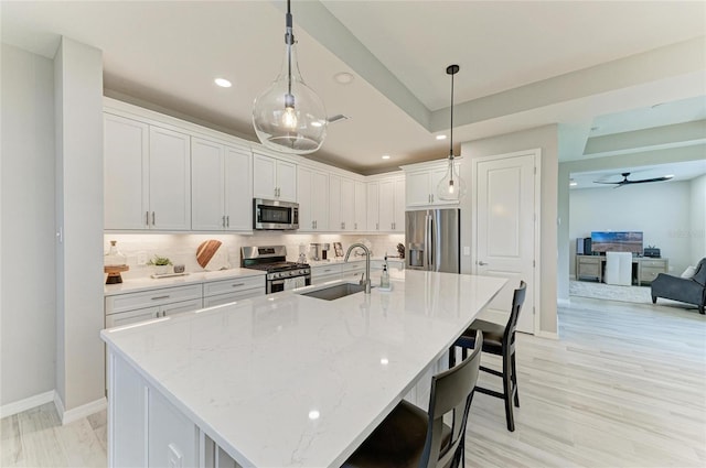 909 Crosswind Ave, Sarasota, FL 34240 - kitchen with appliances with stainless steel finishes, a sink, a breakfast bar area, white cabinets, and decorative backsplash