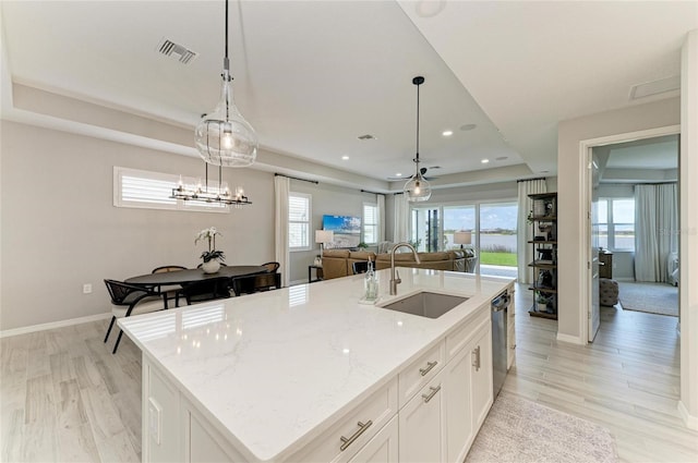 909 Crosswind Ave, Sarasota, FL 34240 - kitchen featuring a sink, open floor plan, dishwasher, light wood-type flooring, and white cabinets