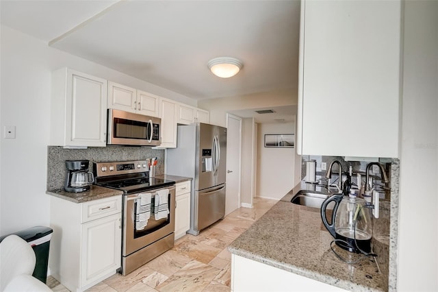 2425 Gulf Of Mexico Dr Unit 14B, Longboat Key, FL 34228 - kitchen with stainless steel appliances, decorative backsplash, a sink, white cabinetry, and light stone counters