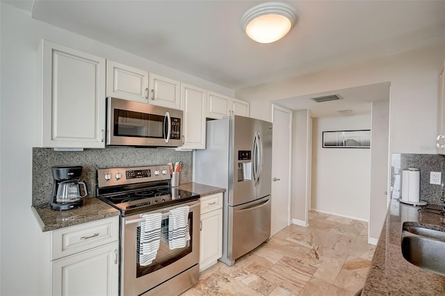 2425 Gulf Of Mexico Dr Unit 14B, Longboat Key, FL 34228 - kitchen with appliances with stainless steel finishes, decorative backsplash, baseboards, white cabinets, and dark stone countertops