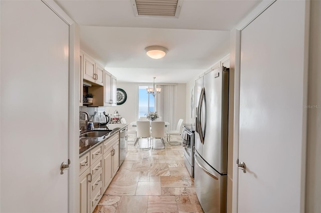 2425 Gulf Of Mexico Dr Unit 14B, Longboat Key, FL 34228 - kitchen with appliances with stainless steel finishes, a sink, dark countertops, stone tile floors, and a chandelier