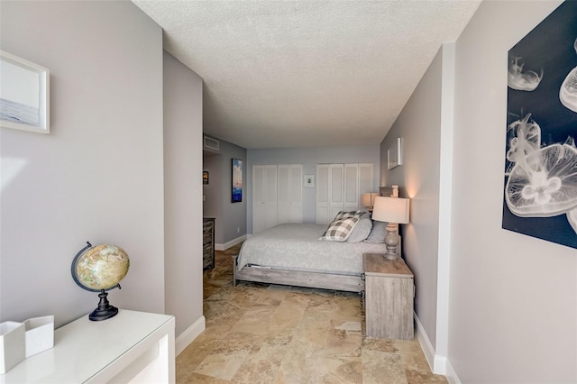2425 Gulf Of Mexico Dr Unit 14B, Longboat Key, FL 34228 - bedroom featuring two closets, baseboards, and a textured ceiling
