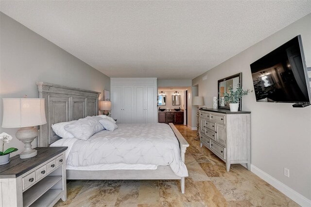 2425 Gulf Of Mexico Dr Unit 14B, Longboat Key, FL 34228 - bedroom with baseboards, connected bathroom, and a textured ceiling