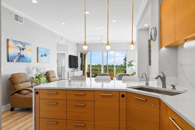 5450 Eagles Point Cir Unit 404, Sarasota, FL 34231 - kitchen with a sink, open floor plan, crown molding, light wood finished floors, and hanging light fixtures