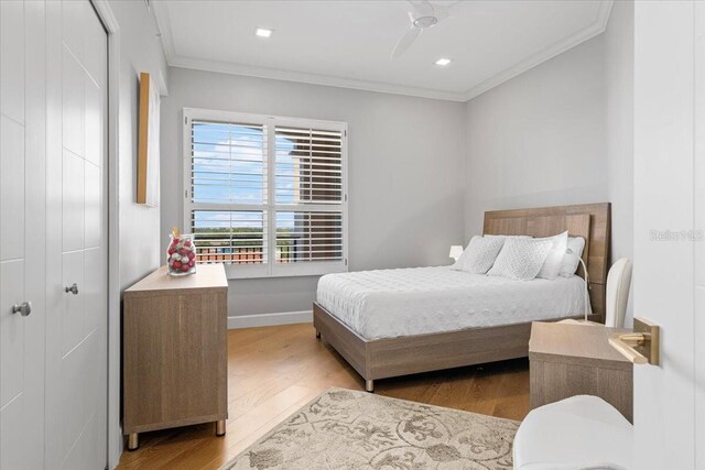 5450 Eagles Point Cir Unit 404, Sarasota, FL 34231 - bedroom featuring wood finished floors, ornamental molding, a ceiling fan, baseboards, and a closet