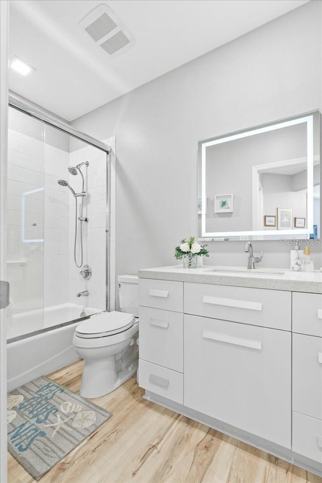 5450 Eagles Point Cir Unit 404, Sarasota, FL 34231 - bathroom featuring vanity, wood finished floors, toilet, and enclosed tub / shower combo