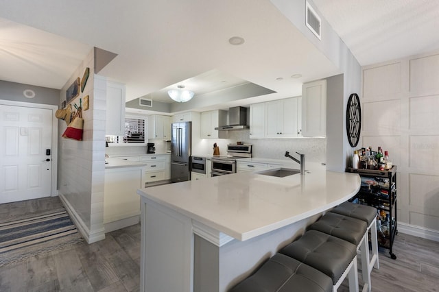 1445 Gulf Of Mexico Dr Unit 203, Longboat Key, FL 34228 - kitchen with wall chimney exhaust hood, stainless steel appliances, wood finished floors, and a kitchen breakfast bar