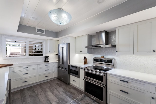 1445 Gulf Of Mexico Dr Unit 203, Longboat Key, FL 34228 - kitchen featuring wall chimney range hood, appliances with stainless steel finishes, dark wood-style floors, light countertops, and decorative backsplash