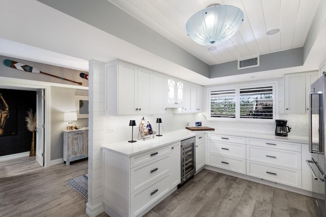 1445 Gulf Of Mexico Dr Unit 203, Longboat Key, FL 34228 - kitchen featuring beverage cooler, white cabinetry, light countertops, light wood-type flooring, and decorative backsplash