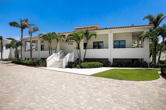 1445 Gulf Of Mexico Dr Unit 203, Longboat Key, FL 34228 - view of front of home with a tiled roof, stucco siding, curved driveway, stairway, and a front yard