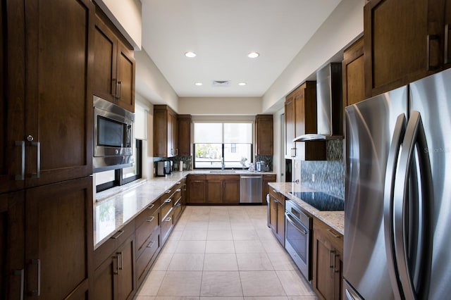 1445 Gulf Of Mexico Dr Unit 203, Longboat Key, FL 34228 - kitchen with stainless steel appliances, wall chimney exhaust hood, light stone counters, light tile patterned floors, and backsplash