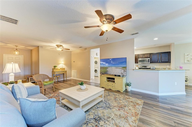 7410 61st St E, Palmetto, FL 34221 - living area featuring stacked washer / dryer, a ceiling fan, and light wood-style floors