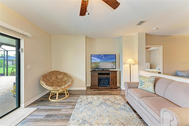 7410 61st St E, Palmetto, FL 34221 - living area featuring wood finished floors, ceiling fan, a textured ceiling, and a fireplace