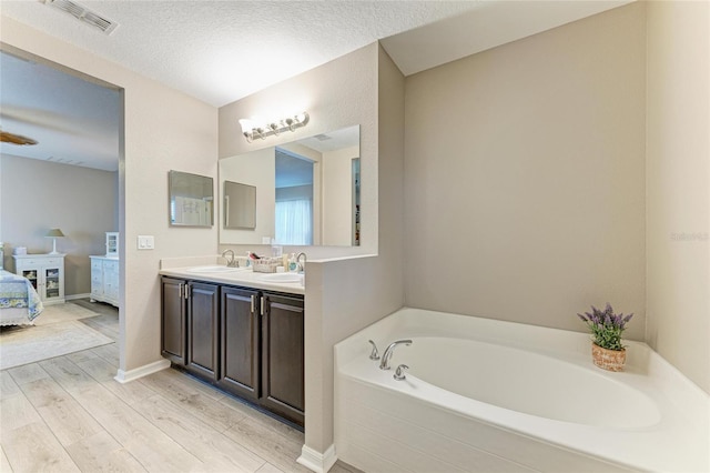 7410 61st St E, Palmetto, FL 34221 - ensuite bathroom with a bath, double vanity, wood finished floors, and a textured ceiling