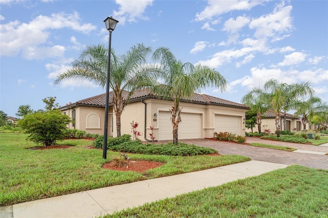 12515 Garibaldi Ln, Venice, FL 34293 - mediterranean / spanish home featuring decorative driveway, stucco siding, an attached garage, a front yard, and a tile roof