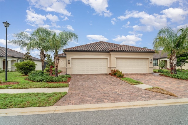 12515 Garibaldi Ln, Venice, FL 34293 - mediterranean / spanish house with decorative driveway, stucco siding, a tiled roof, and an attached garage