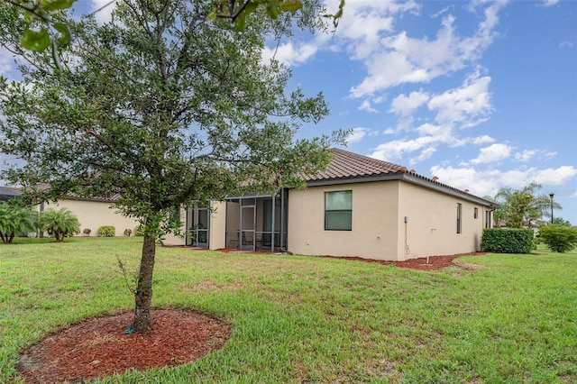 12515 Garibaldi Ln, Venice, FL 34293 - rear view of house with stucco siding, a yard, a tile roof, and a sunroom