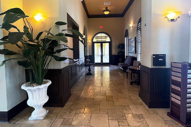 12515 Garibaldi Ln, Venice, FL 34293 - entryway featuring stone tile flooring, arched walkways, french doors, ornamental molding, and a towering ceiling