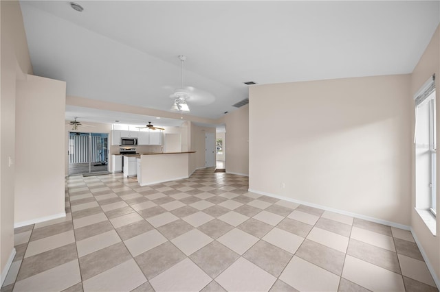1314 SE 15th Ter, Cape Coral, FL 33990 - unfurnished living room with a ceiling fan, plenty of natural light, baseboards, and light tile patterned floors