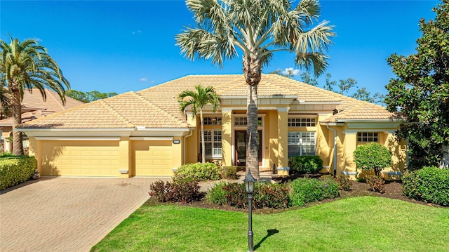 7081 Grassland Ct, Sarasota, FL 34241 - view of front facade featuring an attached garage, a tile roof, decorative driveway, a front lawn, and stucco siding