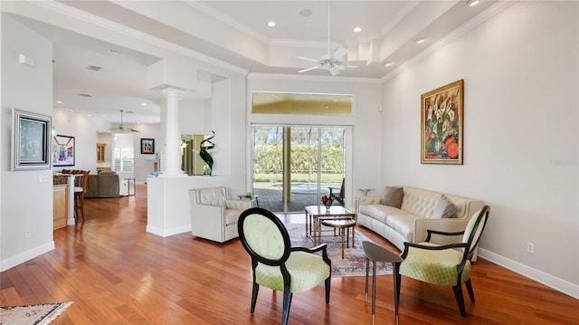 7081 Grassland Ct, Sarasota, FL 34241 - living area featuring a ceiling fan, ornate columns, light wood finished floors, a raised ceiling, and crown molding