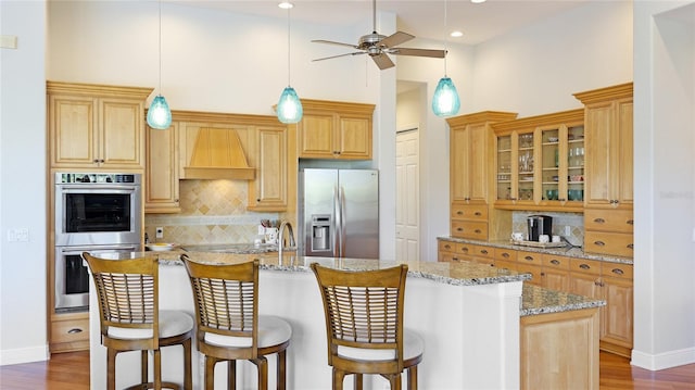 7081 Grassland Ct, Sarasota, FL 34241 - kitchen with appliances with stainless steel finishes, backsplash, custom range hood, an island with sink, and ceiling fan