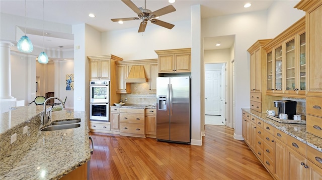 7081 Grassland Ct, Sarasota, FL 34241 - kitchen with appliances with stainless steel finishes, custom exhaust hood, a ceiling fan, light wood-style floors, and backsplash