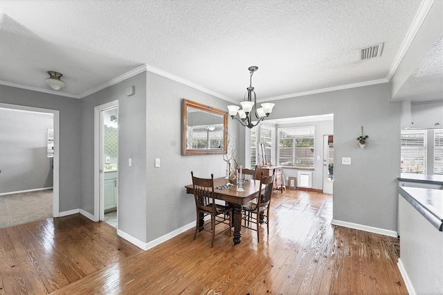304 34th St W, Bradenton, FL 34205 - dining space with hardwood / wood-style floors, a textured ceiling, a chandelier, baseboards, and ornamental molding