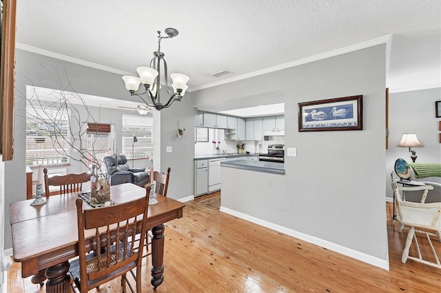 304 34th St W, Bradenton, FL 34205 - dining space with a chandelier, crown molding, light wood-style floors, baseboards, and a textured ceiling
