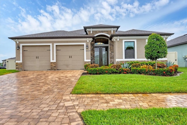 6636 35th Ct E, Sarasota, FL 34243 - prairie-style home featuring stone siding, decorative driveway, an attached garage, and a front lawn