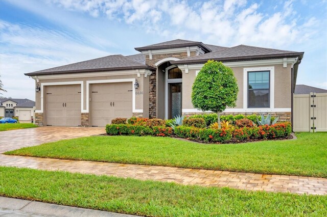 6636 35th Ct E, Sarasota, FL 34243 - prairie-style house featuring stone siding, an attached garage, decorative driveway, a front lawn, and roof with shingles