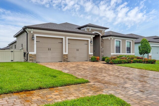 6636 35th Ct E, Sarasota, FL 34243 - prairie-style house with stone siding, an attached garage, decorative driveway, and a gate