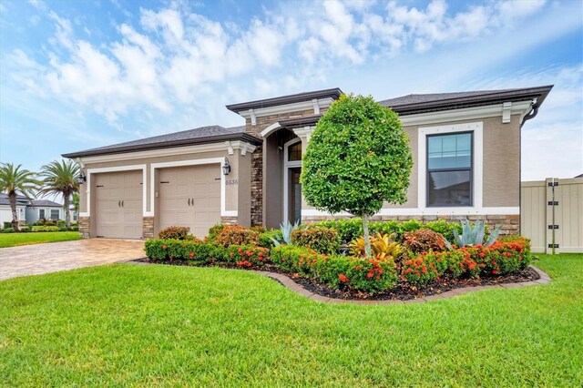 6636 35th Ct E, Sarasota, FL 34243 - view of front of house featuring stone siding, decorative driveway, an attached garage, and a front lawn