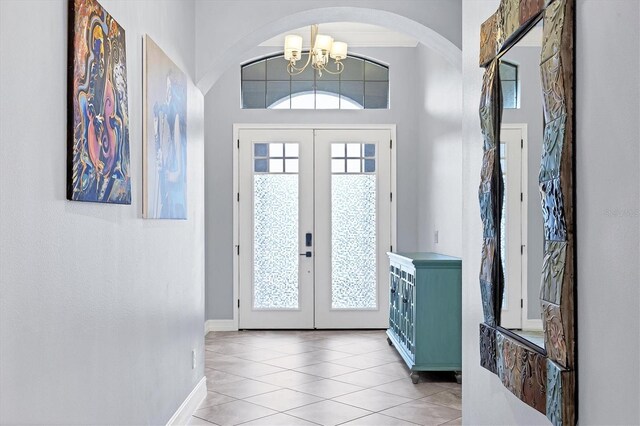 6636 35th Ct E, Sarasota, FL 34243 - foyer featuring french doors, arched walkways, a chandelier, light tile patterned flooring, and baseboards