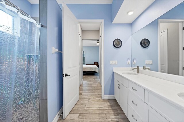 6636 35th Ct E, Sarasota, FL 34243 - ensuite bathroom with double vanity, a ceiling fan, wood finished floors, curtained shower, and baseboards