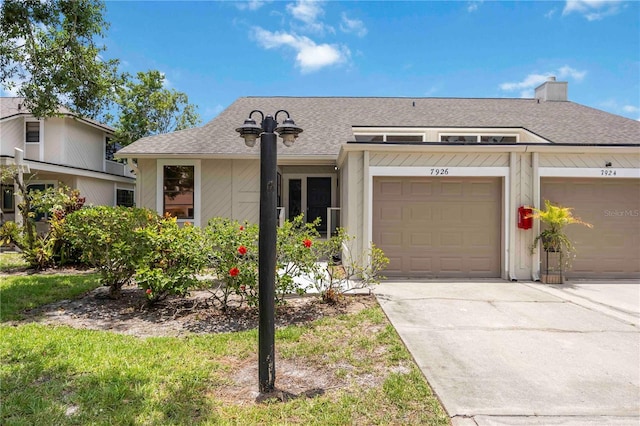 7926 Woodpointe Ct Unit 29, Sarasota, FL 34238 - view of front facade featuring driveway, a shingled roof, a chimney, and an attached garage