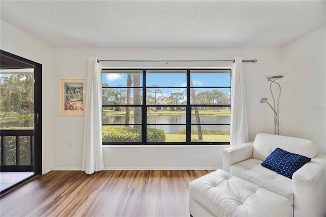 7926 Woodpointe Ct Unit 29, Sarasota, FL 34238 - sitting room with wood finished floors, a water view, a textured ceiling, and baseboards