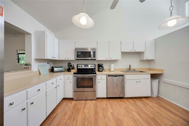7926 Woodpointe Ct Unit 29, Sarasota, FL 34238 - kitchen with stainless steel appliances, a sink, vaulted ceiling, white cabinets, and light wood-style flooring