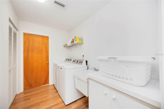 7926 Woodpointe Ct Unit 29, Sarasota, FL 34238 - washroom featuring washing machine and dryer, light wood-type flooring, a textured ceiling, and a sink