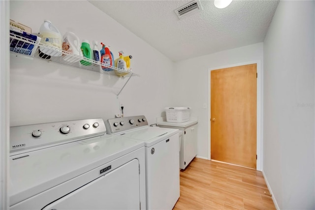 7926 Woodpointe Ct Unit 29, Sarasota, FL 34238 - washroom with washing machine and clothes dryer, cabinet space, light wood-style floors, a textured ceiling, and baseboards