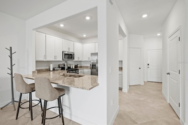 14835 Lyla Ter, Bradenton, FL 34211 - kitchen with stainless steel appliances, light stone counters, white cabinets, a breakfast bar area, and a peninsula