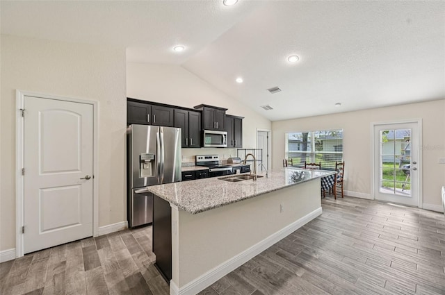 4610 Clarke St, North Port, FL 34286 - kitchen with appliances with stainless steel finishes, a sink, light wood-style floors, a center island with sink, and vaulted ceiling