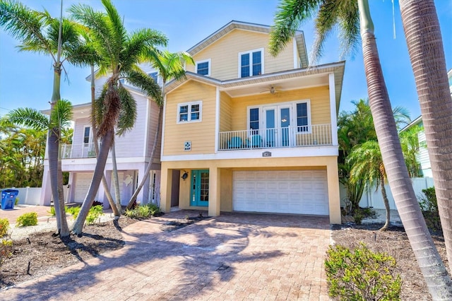 145 50th St, Holmes Beach, FL 34217 - coastal inspired home featuring french doors, a balcony, a garage, decorative driveway, and a ceiling fan