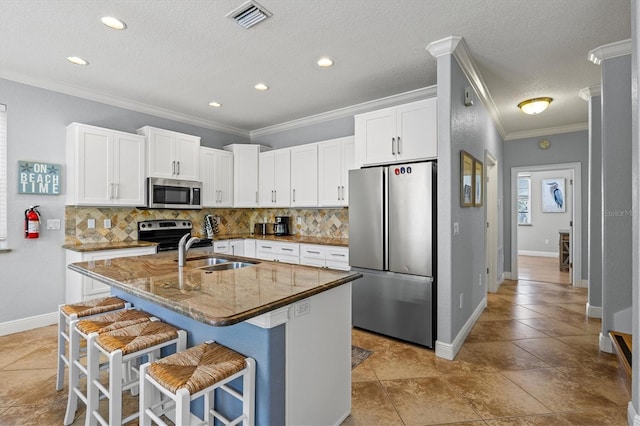 145 50th St, Holmes Beach, FL 34217 - kitchen featuring appliances with stainless steel finishes, crown molding, tasteful backsplash, a kitchen island with sink, and a kitchen breakfast bar